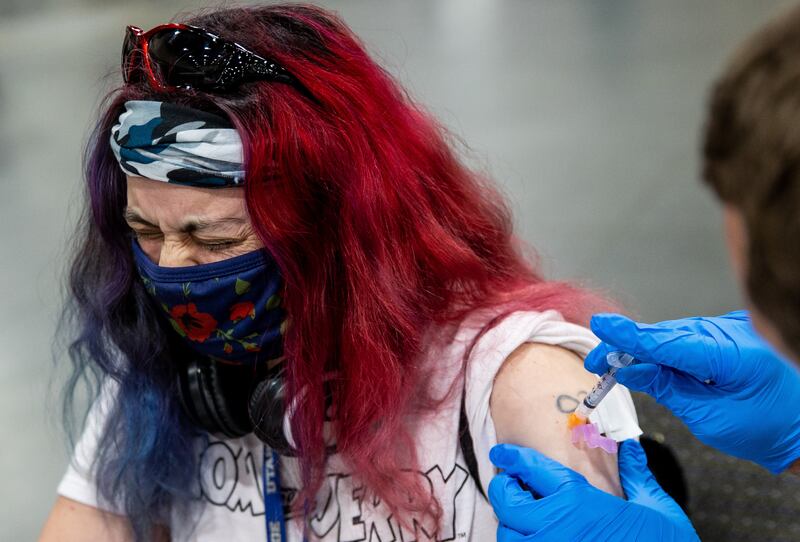 Elizabeth Griego looks away as she gets her first dose of the Moderna COVID-19 vaccine.