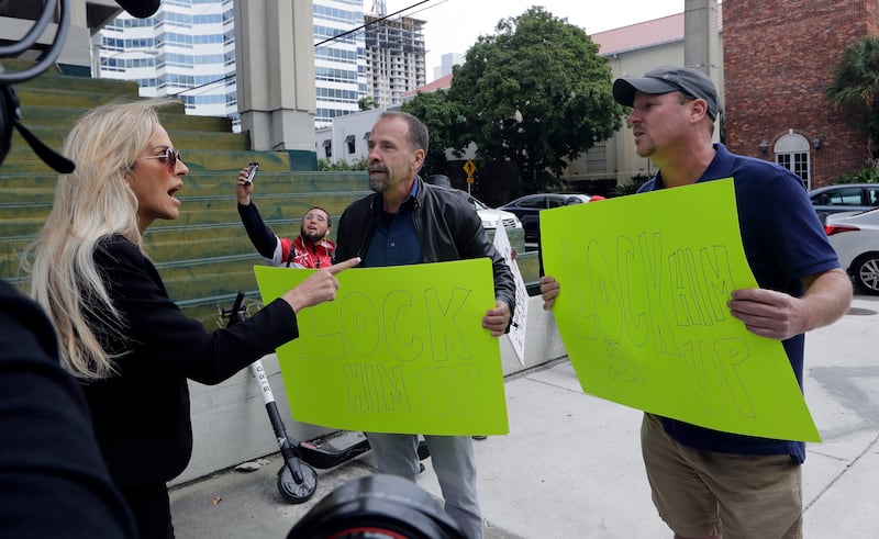 People holding signs reading "Lock Him Up" argue with a counter protestor outside of the federal courthouse where Roger Stone, a confidant of President Donald Trump, has a hearing, Friday, Jan. 25, 2019, in Fort Lauderdale, Fla. Stone was arrested Friday