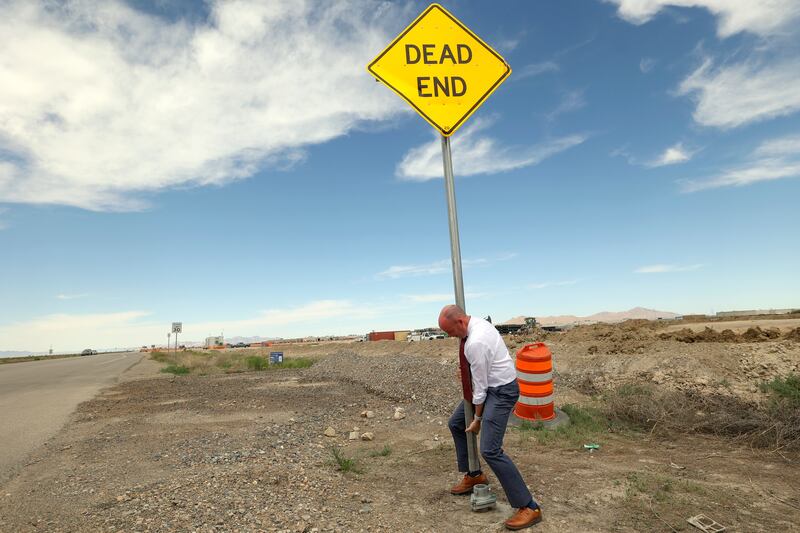 Gov. Spencer Cox takes down a “dead end” sign on the road leading to the new Utah State Correctional Facility on Wednesday.