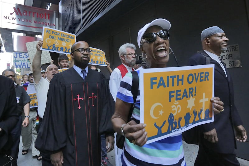 Clergy leaders with PICO (People Improving Communities through Organizing) Action Fund and their local federation, Faith in New York, demonstrate outside the hotel in New York's Times Square, Tuesday, June 21, 2016, where Republican presidential candidate