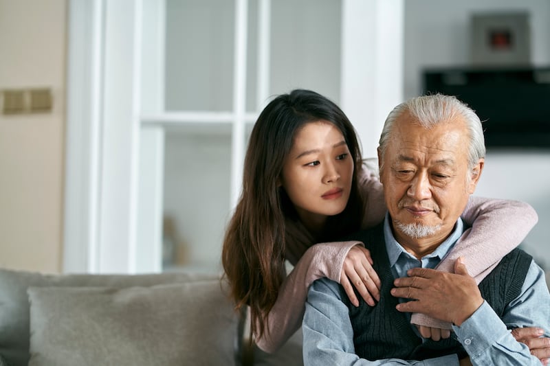 A woman puts her arms around her father.
