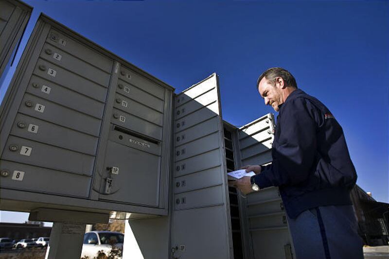 Bob Torrance, a letter carrier for the U.S. Postal Service, checks mail at a locked neighborhood box in Salt Lake City.