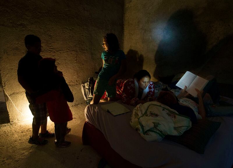 The children play in the light while Maria and Kate Savage read during a rainstorm in Jerez, Guatemala, on Tuesday, Oct. 16, 2018. Electricity is expensive so lights are used sparingly.