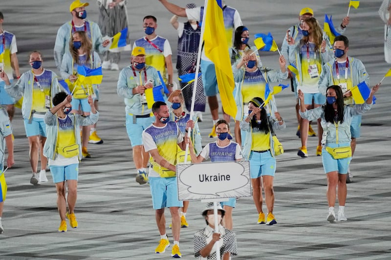 Olena Kostevych and Bogdan Nikishin, of Ukraine, carry their country’s flag at the 2020 Summer Olympics.
