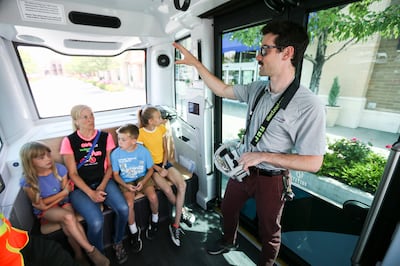 Colin Timm, deployment engineer with EasyMile, explains to Julie Willoughby and her children how the driverless shuttle works as they take a ride at Station Park in Farmington on Monday, June 17, 2019.