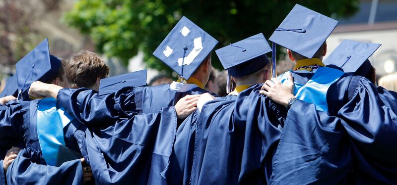 A group of friends stand for photos after their graduation from Skyline High School in Salt Lake City.