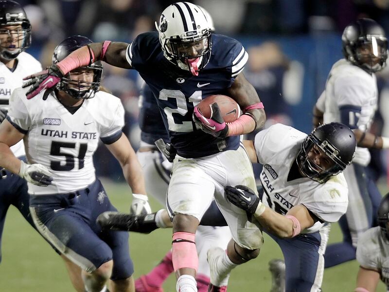 BYU’s Jamaal Williams, center, fights for yardage as Utah State’s McKade Brady attempts to bring him down Oct. 5, 2012.
