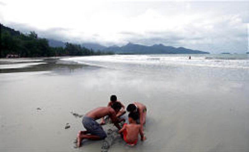 Young tourists play on a deserted beach on the island of Koh Chang in southern Thailand.
