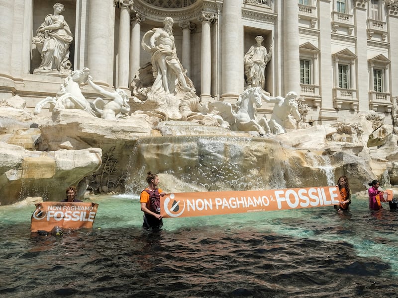 Last Generation environmentalists show a banner against the use of fossil fuels in the Trevi Fountain in Rome, Sunday, May 21, 2023.