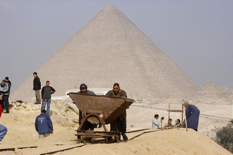 Egyptian archaeology workers ferry sand Monday in trolleys on rail tracks in front of the Great Pyramid in Giza, near tombs of workers.