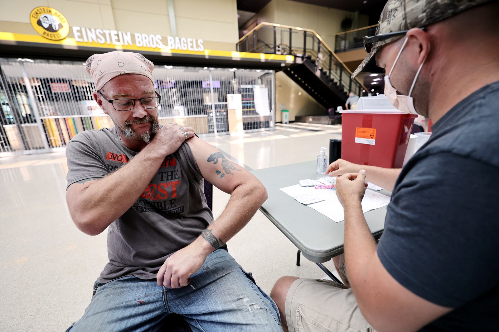 Garrett Litz pulls up his sleeve prior to getting a COVID-19 vaccination from Utah Army National Guardsman Colton Shakespear.