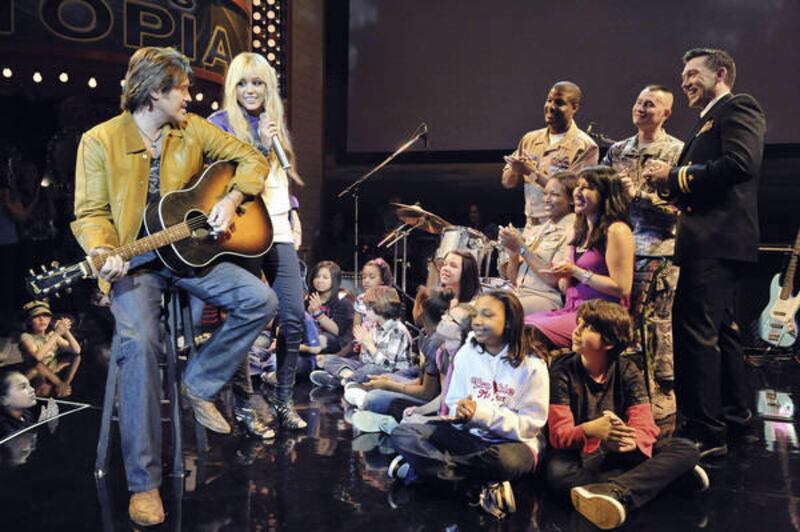 This image provided by the Disney Channel shows Miley Cyrus performing with Billy Ray Cyrus, left, during taping Friday March 12, 2010 of the Disney Channel's series, "Hannah Montana" celebrating military families before an audience of families of service