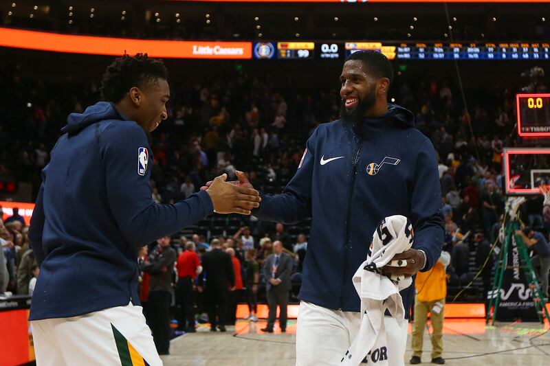 Utah Jazz guard Donovan Mitchell (45) shakes hands with Royce O'Neale (23) after pouring a bottle of water on him during a post game interview after beating the Cleveland Cavaliers at the Vivint Smart Home Arena in Salt Lake City on Friday, Jan. 18, 2019.