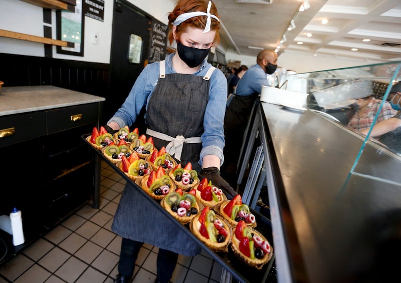 Claire Isom places fruit tarts into a display case at Gourmandise in Salt Lake City on Thursday, April 8, 2021.