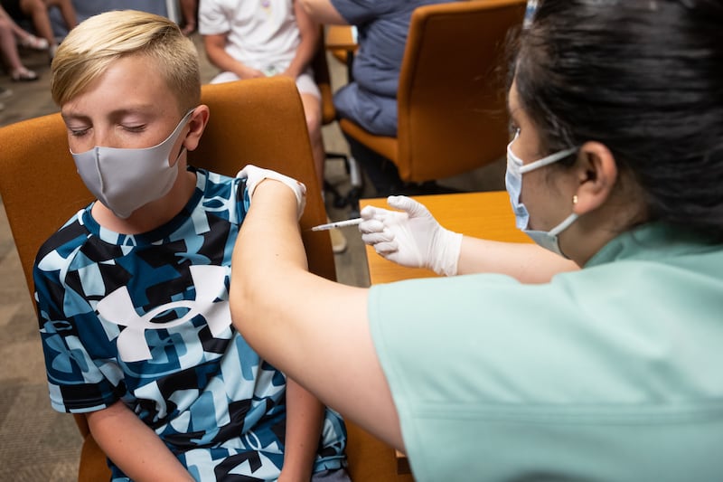 Jack Allen, 12, closes his eyes as he gets a shot of the Pfizer-BioNTech COVID-19 vaccine..