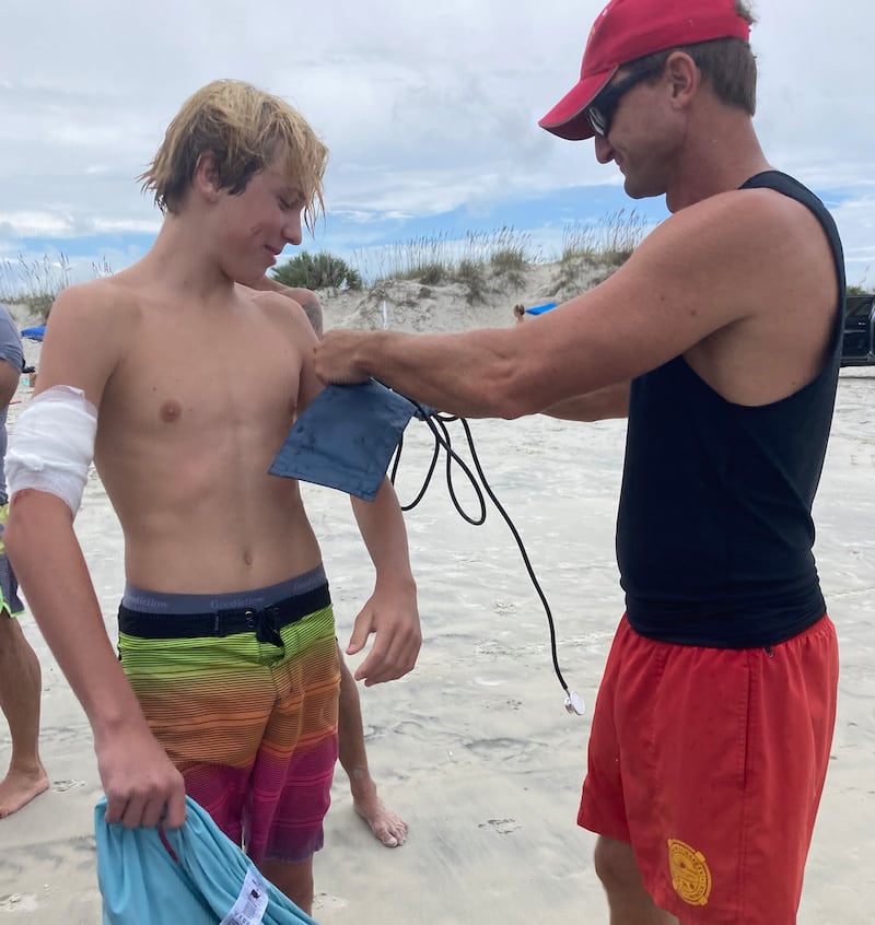 A lifeguard treats Doyle Nielsen after he was bit by a shark while surfing in Florida on Sept. 9.