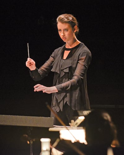 Stephanie Rhodes Russell conducting an orchestra. Russell is the founder of Women's Artistic Leadership Initiative.