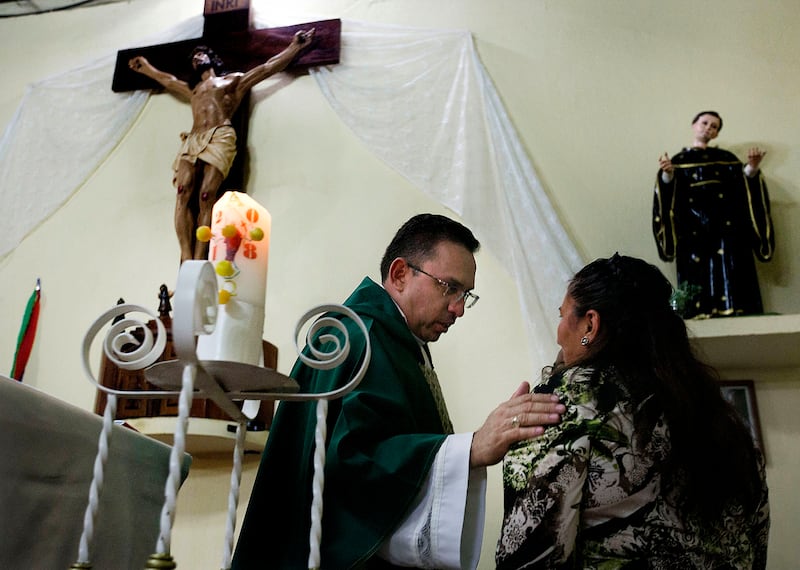Father Nelson Melendez prays for Maria Santiago during a church service at San Nicolas in Jerez, Guatemala, on Sunday, Oct. 14, 2018. “Bless you, Maria, and your children, Patrick and Sarai," he says in Spanish. "May God give you the strength to separate