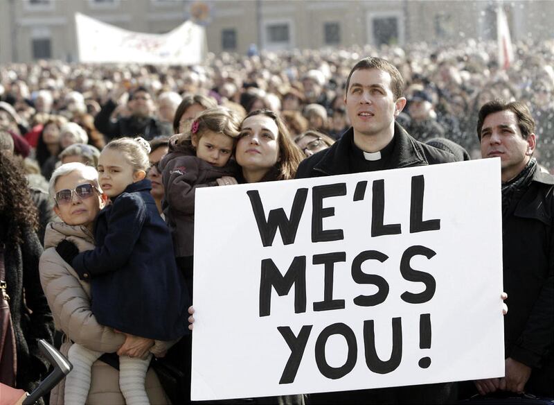 A priest displays a placard in St. Peter's Square at the Vatican as he follows Pope Benedict XVI reciting the Angelus prayer from the window of his apartments on Sunday.