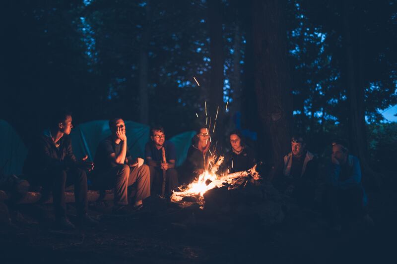 A group of friends sit and talk around a campfire in Algonquin Park in Canada.