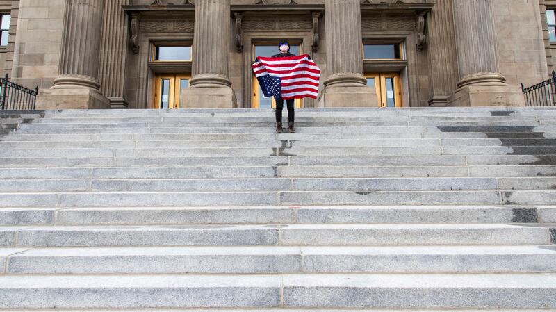 A student holds a U.S. Flag upside down at the Idaho Capitol Building in Downtown Boise.