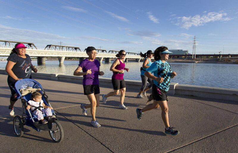 Navecia Hill, 28, left, runs with her 1-year-old daughter, Noelle, alongside other members of Native Fit around Tempe Town Lake in Tempe, Ariz., on Saturday, July 21, 2012. Diana Yazzie-Devine, president of Native American Connections, knew that many Nati