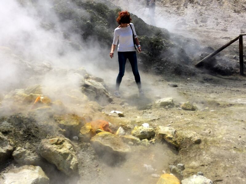 In this photo taken on April 30, 2016, a woman takes a close look at a steaming fumarola at the Solfatara crater bed, in the Phlegraean Fields near Naples, Italy.