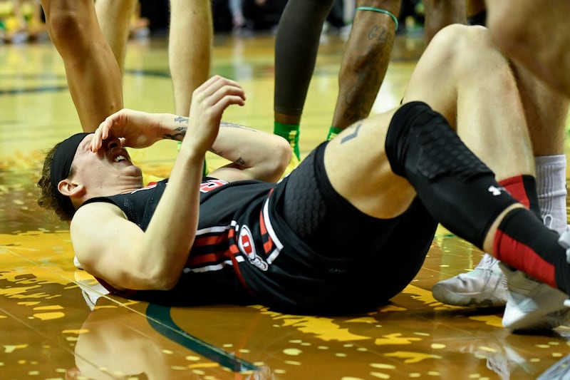Utah guard Gabe Madsen reacts to a knee injury after going for a rebound against Oregon, Jan. 28, 2023, in Eugene, Ore.