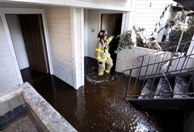 Salt Lake City firefighter Alex Hingham walks through a flooded entryway while trying to help residents recover items after a fire at the Seasons at Pebble Creek Apartments on Wednesday, Aug. 8, 2018.