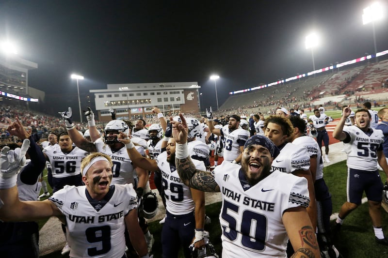Utah State players sing the school’s song while celebrating with fans after winning 26-23 against Washington State.
