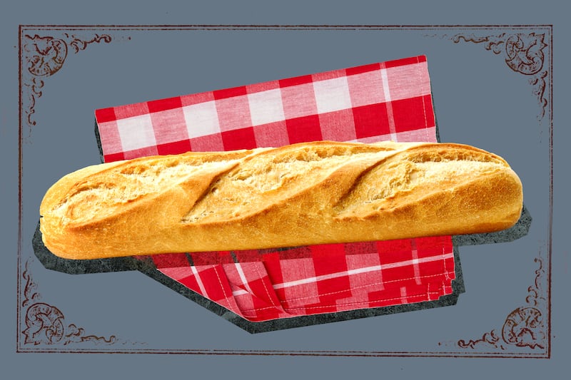A loaf of baked bread on a red gingham check cloth with a gray background.