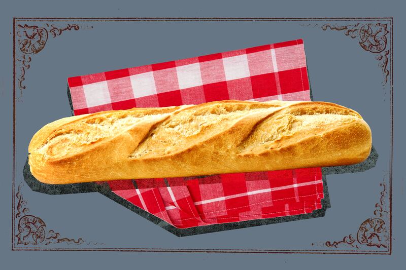 A loaf of baked bread on a red gingham check cloth with a gray background.