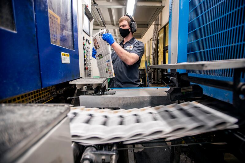 A press worker checks a newspaper of the Deseret News after it is printed in West Valley City on Dec. 31, 2020.