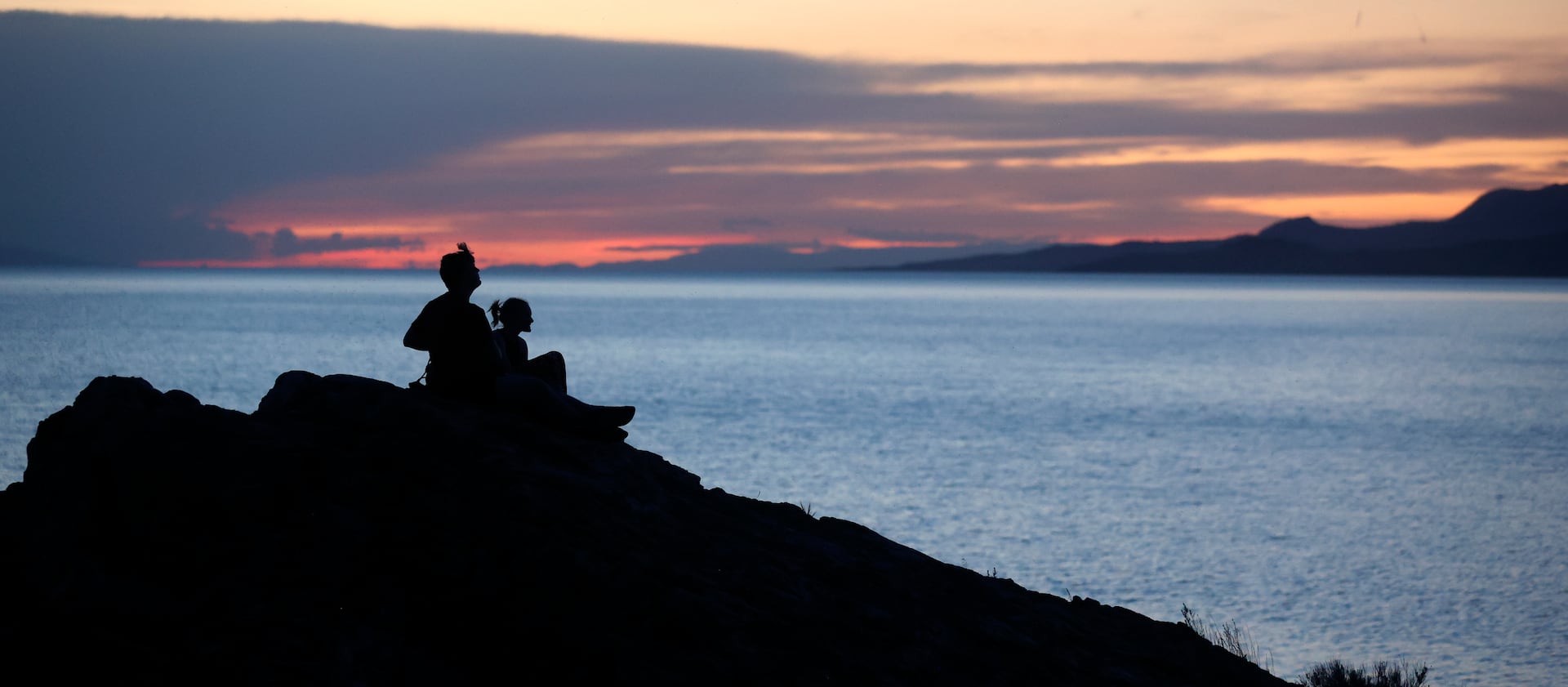 Two people watch the sunset over the Great Salt Lake from Ladyfinger Point on Antelope Island on June 5, 2023.