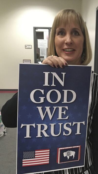 Wyoming State Rep. Cheri Steinmetz,R-Lingle, on March 6, 2018, shows an example of an “In God We Trust” placard in Cheyenne, Wyo. Steinmetz sponsored a bill that would allow people to donate such placards for display in prominent places in state buildings
