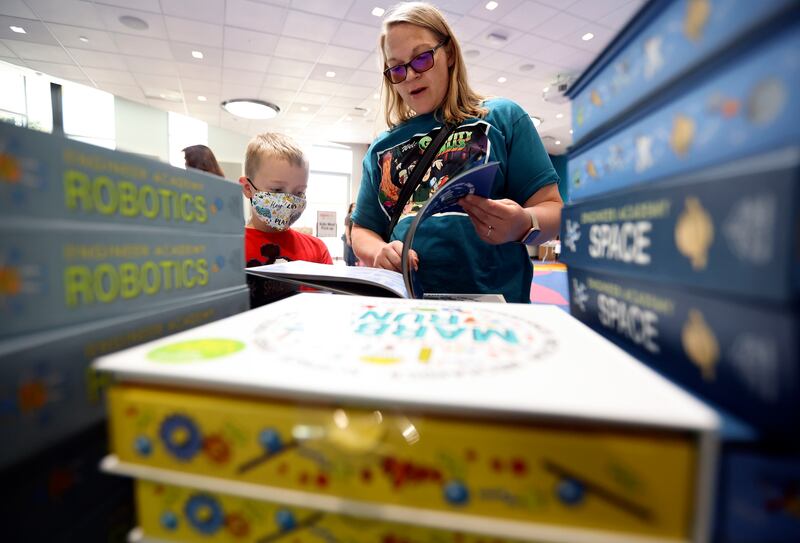 Toby Berry picks out a book with the help of his mother, Charisse Berry, at the Salt Lake County Library in Kearns on Thursday, June 10, 2021. One thousand children will receive shoes, books and a meal through a partnership with the Salt Lake County Library, Operation Warm, MolinaCares, The Sorenson Legacy Foundation and the Utah Food Bank.