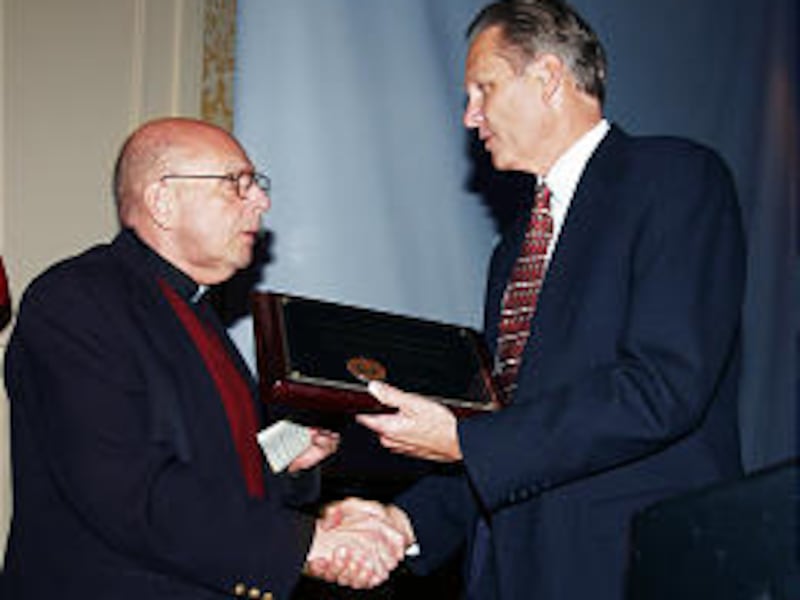 On behalf of the Most Rev. George Niederauer, Monsignor J. Terrence Fitzgerald, left, accepts the Guardian of Light Award from Dan Paxton. Bishop Niederauer is chairman of the Utah Coalition Against Pornography.