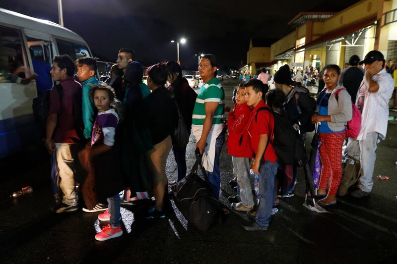 Migrants hoping to reach the U.S. wait in line to board a bus toward Honduras' border with Guatemala, as hundreds of migrants set off by bus or on foot from a main bus station in San Pedro Sula, Honduras, late Monday, Jan. 14, 2019. Yet another caravan of
