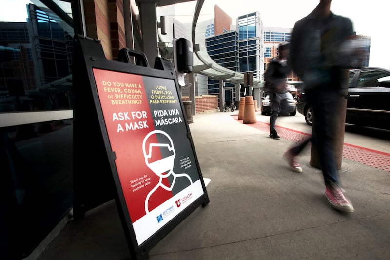 Visitors to the University of Utah Hospital in Salt Lake City walk past signs offering information about masks for those who are experiencing fever, cough or difficulty breathing on Monday, March 9, 2020. The hospital is preparing for potential COVID-19 patients.