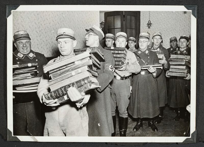 This photo released by Yad Vashem, World Holocaust Remembrance Center, shows German Nazis carry Jewish books, presumably for burning, during Kristallnacht intake most likely in the town of Fuerth, Germany on Nov. 10, 1938.