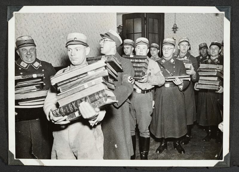 This photo released by Yad Vashem, World Holocaust Remembrance Center, shows German Nazis carry Jewish books, presumably for burning, during Kristallnacht intake most likely in the town of Fuerth, Germany on Nov. 10, 1938.