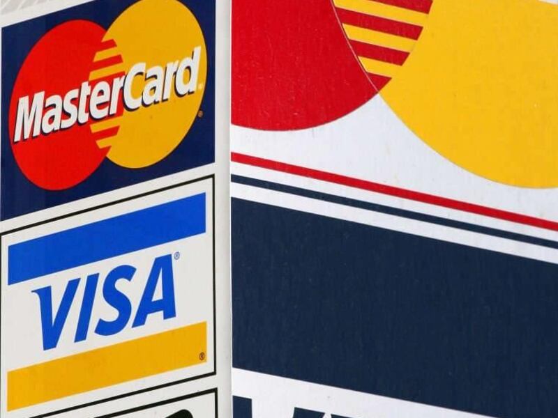 Credit card signs are posted outside a New York parking garage. Consumer credit debt is increasing while household debt is decreasing.