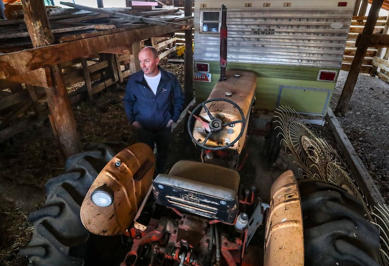 Spencer Cox, governor of Utah, stands near an old Case tractor that he learned to drive as a child on his family’s farm.