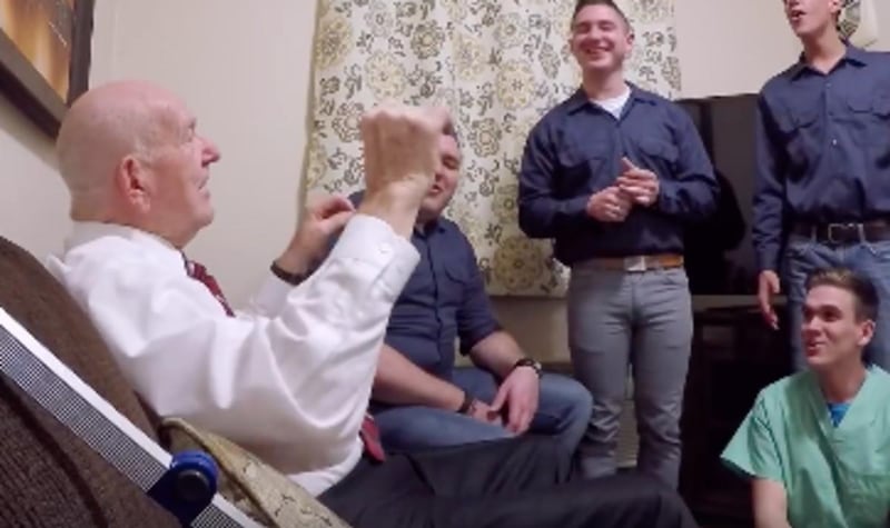 Members of BYU's Vocal Point are shown singing to an elderly man.