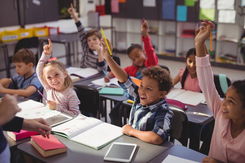 Students raise their hands in a classroom.