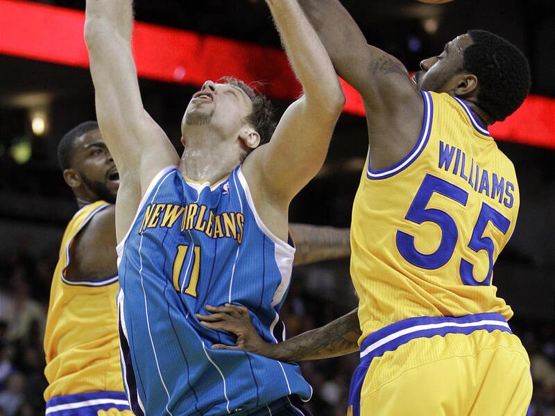 New Orleans Hornets' David Andersen (11) has his shot blocked by Golden State Warriors' Dorell Wright, left, as Reggie Williams (55) assists during the second half of an NBA basketball game Tuesday, Feb. 15, 2011, in Oakland, Calif.