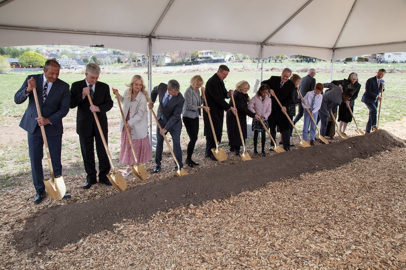 A small group of invited guests turns shovels of dirt at the groundbreaking for the Lindon Utah Temple on April 23, 2022. Elder Kevin W. Pearson, a General Authority Seventy and Utah Area president, and his wife, Sister June Pearson, are at the center.