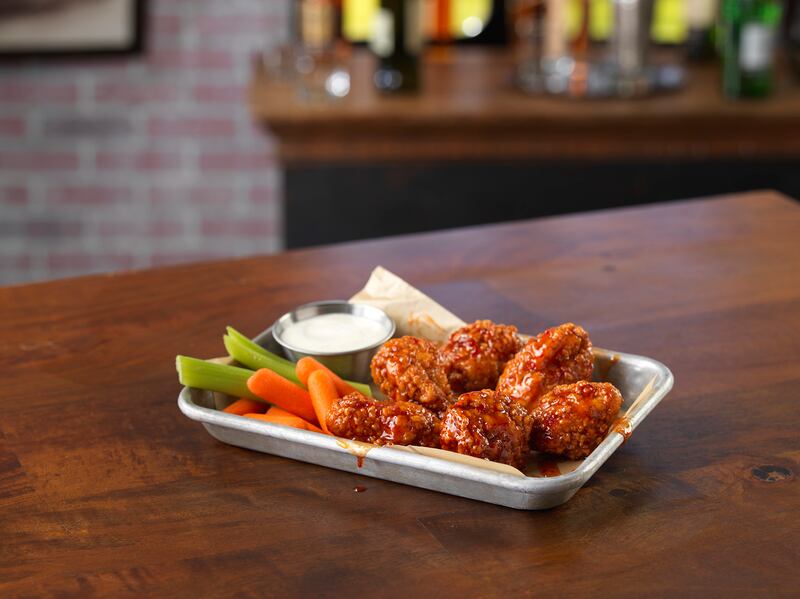 Hot wings and some sides are pictured on a plate.