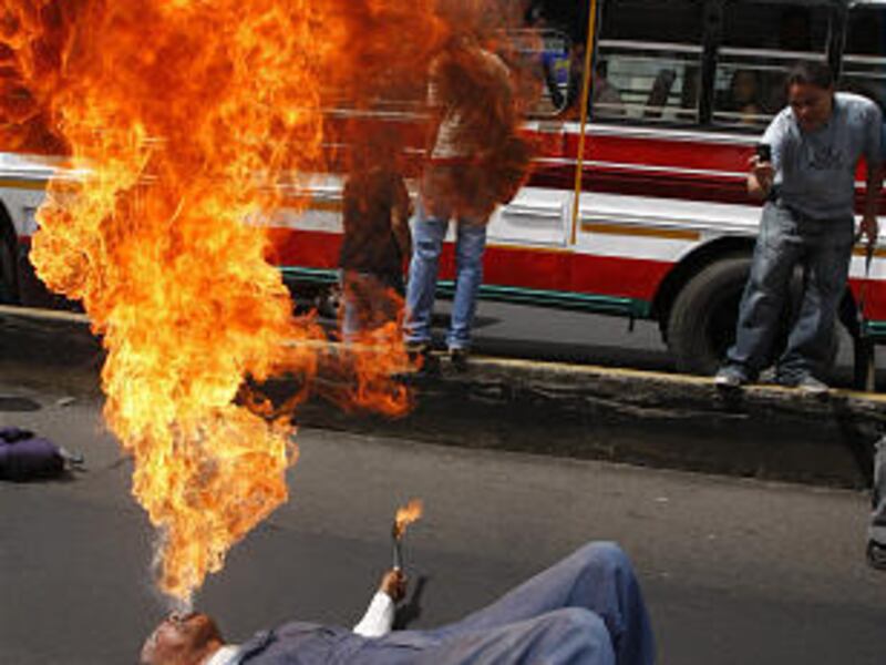 A clown going by the name Ivan performs a fire-spitting act near a bus in San Salvador, El Salvador, during a protest Thursday of professional clowns against the common practice of armed bandits who pose as clowns to rob people on buses and other forms of