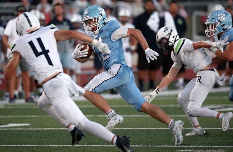 Sky View’s Brevin Egbert runs with the ball as he looks at Ridgeline’s Trace Dustin during a varsity football game.